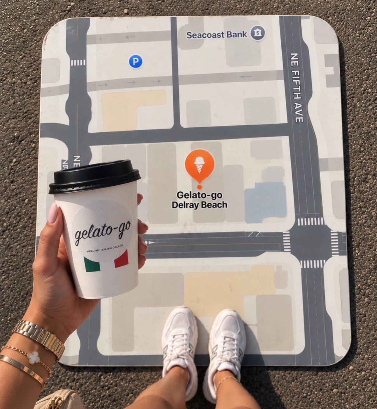 A Gelato-go coffee cup over the shop's map mat showing Gelato-go Delray Beach on East Atlantic Avenue by NE Fifth Avenue